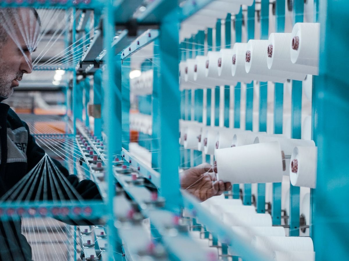 Textile worker inspecting thread spools on factory machinery